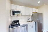 Located on the seventh floor at 1845 Summit Pl NW in Washington, DC's vibrant Adams Morgan neighborhood, this studio unit offers a well-considered layout that makes efficient use of its intimate footprint. The main living area is finished with warm hardwood flooring that runs throughout, complemented by neutral beige walls and generous natural light streaming in through large windows fitted with blinds. Views of the surrounding neighborhood's treetops and cityscape add a pleasant outdoor connection to the interior.

The kitchen is thoughtfully appointed with white shaker-style cabinetry extending to the ceiling, a classic white subway tile backsplash, and a full suite of stainless steel appliances including a gas range, over-the-range microwave, dishwasher, and full-size refrigerator. A single-basin sink with a modern faucet completes the functional workspace.

The bathroom presents a clean, all-white aesthetic with light tile flooring, a shower/tub combination, toilet, and a vanity with storage. Recessed lighting keeps the space bright and practical.

A dedicated laundry area features a stacked full-size washer and dryer unit, an uncommon convenience at this scale. The electrical panel is also accessible within this alcove. The open living space benefits from a wall-mounted thermostat and ceiling light fixture, rounding out a move-in-ready unit.