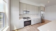 This thoughtfully designed 2-bedroom, 2-bathroom residence in South Amboy, NJ offers a bright and modern living experience across a single, efficiently laid-out floor. Light-toned hardwood flooring flows seamlessly throughout, complementing the crisp white walls and recessed lighting that give the space a clean, contemporary feel.

The open-concept kitchen and living area serves as the heart of the home. The kitchen is well-appointed with gray shaker-style cabinetry extending to the ceiling for generous storage, stainless steel appliances including a gas range, built-in microwave, and full-size refrigerator, a herringbone tile backsplash, and light quartz countertops. A center island adds additional prep and dining space.

The living room is bathed in natural light through a bank of large windows offering views of the surrounding South Amboy streetscape. The spacious primary bedroom features a wide window with outdoor views, while the second bedroom is bright and versatile. A well-appointed hallway with louvered storage doors connects the living spaces to both bedrooms.

The primary bathroom features large-format tile flooring, a glass-enclosed walk-in shower with textured tile surround, warm wood vanity cabinetry, and a wide mirror. The second bathroom is clean and functional, finished with matching tile and neutral tones throughout.