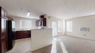 Located at 7410 South Hayford Road in Spokane, Washington, this single-floor unit offers a thoughtfully arranged layout designed for comfortable everyday living. The open-concept kitchen and living area serves as the heart of the space, bathed in natural light streaming through large windows dressed with vertical blinds. The kitchen is well-equipped with rich dark-wood cabinetry, light countertops, and black appliances including a range, built-in microwave, dishwasher, and refrigerator. A peninsula provides a natural divide between the kitchen and the carpeted living area, which opens to a sliding glass door for additional light and access.

The bedrooms feature plush carpeting, generous closet space with wire shelving, and windows that invite natural light. A hallway connects the private areas of the unit, with a walk-in closet adding practical storage. Two full bathrooms are finished with wood-look tile flooring and include tub-shower combinations with clean white surrounds and chrome fixtures.

Throughout the unit, neutral tones, white panel doors, and consistent wood-look flooring in the wet areas create a cohesive, clean aesthetic that is both functional and inviting.