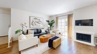Located in Woodland Hills, CA, this two-story, 3-bedroom, 3-bathroom home offers a thoughtfully designed layout spread across two floors. The main level features a bright, open-concept living, dining, and kitchen area bathed in natural light from multiple sliding glass doors and windows. The living room centers around a classic fireplace and flows seamlessly into the dining area, which is accented by a warm wood-framed mirror and wall sconces. The kitchen is well-appointed with white shaker cabinetry, stainless steel appliances including a gas range, built-in microwave, and dishwasher, complemented by grey countertops and a skylight above that adds additional brightness. Hardwood-style flooring runs throughout the main level, enhancing the cohesive, airy feel. A dedicated laundry room with a full-size washer and dryer adds everyday convenience. Upstairs, the primary bedroom features vaulted ceilings, mirrored closet doors, and a tranquil atmosphere. Three well-maintained bathrooms each include wood-tone flooring and clean, neutral finishes. Two private balconies offer outdoor views of mature trees, palm-lined courtyards, and community amenities including tennis courts, providing a peaceful Southern California retreat.