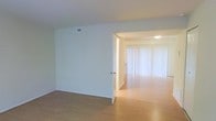 This two-floor space offers a clean, minimalist aesthetic defined by crisp white walls, smooth ceilings, and warm hardwood-style flooring that flows seamlessly across the interior. The layout is thoughtfully designed to maximize openness, with connected living areas that allow natural light to travel freely from room to room. Large vertical blinds adorn expansive windows or sliding glass doors, diffusing generous amounts of natural light and creating a bright, airy ambiance throughout. The open passageway between rooms enhances the sense of spaciousness, making the interior feel welcoming and versatile. HVAC vents are discreetly integrated into the ceiling and walls, ensuring comfort without detracting from the clean visual lines of the space. The neutral color palette — dominated by whites and soft tones — provides a timeless, adaptable backdrop suitable for a variety of uses. The second floor adds dimension to the overall layout, offering additional space and separation between areas. Overall, the space is characterized by its simplicity, functionality, and abundance of natural light, creating a comfortable and inviting environment across both levels.