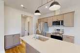 Located at 4100 Wheaton Pl in Howell, Michigan, this two-story home offers a thoughtfully designed layout across two floors. The main level provides a welcoming foundation with a living room, dining room, and a well-appointed kitchen featuring taupe shaker-style cabinetry, quartz countertops, a central island with an undermount sink, stainless steel appliances, and stylish black-and-brass pendant lighting. Light hardwood flooring runs throughout, complementing the home's clean, contemporary aesthetic. A full bathroom and access to the attached garage — complete with an automatic opener — round out the ground floor. The upper level hosts all three bedrooms, including a generously sized primary bedroom bathed in natural light from large windows overlooking the yard. Each bedroom features light hardwood floors and window blinds, with the secondary bedrooms offering comfortable proportions and neighborhood views. Three full bathrooms are distributed across the home, each finished with taupe vanity cabinetry, white quartz countertops, and modern matte black hardware. Five closets provide ample storage throughout. A dedicated laundry room with full-size washer and dryer adds everyday convenience. Bright hallways with recessed lighting connect all spaces, creating a cohesive and functional flow throughout this move-in-ready home.