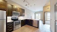 Located in the vibrant East Nashville neighborhood, this one-bedroom, one-bathroom unit offers a thoughtfully designed open-concept layout that maximizes every square foot. The kitchen serves as the centerpiece of the living area, boasting rich dark espresso cabinetry, white quartz countertops, a classic subway tile backsplash, and a full suite of stainless steel appliances including a range, microwave, dishwasher, and refrigerator. Elegant pendant lighting hangs above the kitchen peninsula, while a track lighting system provides additional illumination. Light wood-tone flooring runs throughout the main living areas, lending warmth and continuity to the space. The kitchen flows seamlessly into the living area, which benefits from a large window that fills the room with natural light and offers views of the surrounding neighborhood. The bedroom features plush carpeting, neutral walls, and a generously sized window with views to the outside. The bathroom is finished with light tile flooring, a white vanity with ample counter space, and a tiled tub-shower combination. An in-unit laundry area adds everyday convenience. Stylish gray panel doors and a clean, contemporary color palette complete the modern aesthetic throughout.