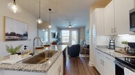 Located at 4101 Glenloch Creek in Matthews, NC, this single-floor residence offers a thoughtfully designed open-concept layout that seamlessly connects the kitchen, dining, and living areas. The kitchen is a standout feature, outfitted with crisp white cabinetry, granite countertops, a large center island with an undermount sink, and a full suite of stainless steel appliances including a refrigerator, dishwasher, range, and over-the-range microwave. Stylish pendant lighting illuminates the island, adding a contemporary touch. Rich wood-look flooring runs throughout the main living areas, contributing to a warm and cohesive aesthetic. The living room is bright and welcoming, benefiting from large windows that invite natural light and provide outdoor views, complemented by a ceiling fan overhead. The bedroom is carpeted for comfort, features a window with natural light, and offers ample space for furnishings. The bathroom continues the home's refined finishes with granite countertops, white cabinetry, a large mirror, and direct access to a walk-in closet with built-in shelving. A stacked Whirlpool washer and dryer unit is conveniently housed in-unit. The overall ambiance is clean, modern, and move-in ready.