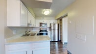 This thoughtfully designed 1-bedroom, 1-bathroom residence at 2801 Park Center Drive offers a clean, modern aesthetic throughout its efficiently laid-out floor plan. The open living area is bathed in natural light, thanks to large sliding glass doors that lead to a private balcony overlooking mature trees and greenery. Light-toned luxury vinyl plank flooring runs through the main living spaces, complementing the bright white walls and textured ceilings that are consistent throughout. A ceiling fan adds comfort to the living area, which also benefits from an additional window fitted with blinds for adjustable light control. The kitchen is well-equipped with stainless steel appliances, including a refrigerator, electric range, over-the-range microwave, and dishwasher. Crisp white shaker-style cabinetry extends to the ceiling, offering generous storage, while the light countertops provide ample workspace. The bedroom features plush wall-to-wall carpeting, a large window for natural light, and direct access to a closet and bathroom hallway. The bathroom area includes a linen closet with built-in shelving for additional storage. A dedicated entrance and separate closet round out this functional and well-organized residence.