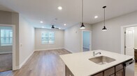 This single-story unit located along Alt US-72 W in Huntsville, Alabama, offers a thoughtfully designed open-concept layout with contemporary finishes throughout. The kitchen serves as the centerpiece of the living area, featuring rich, dark-toned cabinetry with brushed nickel hardware, light quartz countertops, a stainless steel appliance suite including a refrigerator, range, and over-the-range microwave, and a peninsula with an undermount sink. Stylish pendant lights hang above the peninsula, complementing the recessed lighting overhead. The adjoining living area is finished with wood-look plank flooring and includes a ceiling fan, with a window allowing natural light to fill the space.

The bedrooms are carpeted for comfort, each equipped with a ceiling fan and a window with blinds. One bedroom connects to a generously sized walk-in closet outfitted with wire shelving on multiple walls. Two bathrooms mirror each other in design, featuring wood-toned vanities with quartz counters, undermount sinks, and wood-look flooring. One includes a shower-tub combination. The overall aesthetic is clean and neutral, creating a bright, move-in-ready environment.