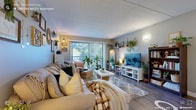 Located at 28 Oyster Bay Rd in Boston, MA, this single-floor residence offers a well-designed layout with multiple bedrooms, a modern kitchen, comfortable living spaces, and a functional hallway connecting it all. The kitchen is outfitted with white shaker cabinetry, granite countertops, stainless steel appliances including a dishwasher and range, and durable wood-look flooring — combining practicality with a clean, contemporary aesthetic. The open living room is bright and welcoming, featuring large sliding glass doors that flood the space with natural light and provide views of the surrounding greenery. Built-in shelving adds character and display space throughout. The bedrooms are generously sized, each with wood-look flooring, windows with outdoor views, and wall-mounted shelving. One bedroom features a dedicated study area, while another is configured to accommodate two occupants with twin beds. The bathroom is finished with a granite-topped vanity, white cabinetry, and a medicine cabinet mirror. A wide central hallway with wood-look flooring connects the rooms and provides ample storage access. Neutral gray tones, warm lighting, and natural elements create a cohesive, inviting atmosphere throughout the entire residence.