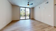 Located at 101 Main St N in Saint Petersburg, FL, this modern one-bedroom, one-bathroom unit offers a thoughtfully designed layout with contemporary finishes throughout. Light-toned hardwood-style flooring flows seamlessly across every room, complementing the clean, neutral palette.

The open-concept kitchen and living area is a standout feature, anchored by a sleek center island with quartz countertops and pendant lighting. The kitchen is outfitted with light wood cabinetry extending to the ceiling, stainless steel appliances, a white tile backsplash, and matte black fixtures — a cohesive blend of modern aesthetics and functionality. Exposed concrete ceiling elements add an industrial touch throughout the space.

The living area connects to a private balcony through expansive floor-to-ceiling sliding glass doors, offering views of a resort-style pool and swaying palm trees. The bedroom is generously sized with large windows that fill the room with natural light and a walk-in closet with wire shelving.

The bathroom features a soaking tub and shower combination with white tile surround, a wide vanity with quartz countertops, warm wood cabinetry, and matte black fixtures. A dedicated in-unit laundry closet with a stacked washer and dryer adds everyday convenience. Ceiling fans in the main living spaces and bedroom complete this well-appointed Florida residence.