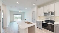 Located at 1617 Enid St in Houston's vibrant 77009 zip code, this well-designed one-bedroom, one-bathroom unit offers a thoughtful layout across a single floor. The open-concept living and kitchen area is bright and airy, anchored by a central island with a undermount sink and crisp white quartz countertops. The kitchen is outfitted with stainless steel appliances — including a refrigerator, range, and built-in microwave — complemented by two-tone cabinetry in white and slate blue, and a classic tile backsplash. Light wood-look flooring flows throughout the main living areas, enhancing the clean, contemporary aesthetic. Recessed lighting and a ceiling fan keep the space comfortable and well-lit. A sliding glass door opens to a private balcony with railing, offering outdoor views and natural light. The bedroom features plush carpeting, a ceiling fan, dual windows overlooking the surroundings, and generous closet storage. The bathroom includes a soaking tub with tiled surround, hardwood-style flooring, and direct access to a well-organized walk-in closet with multi-tier shelving. Additional highlights include in-unit laundry, a hallway, and multiple closets for ample storage throughout.