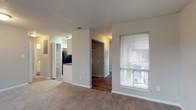 Located at Treeside Park, this single-floor residence offers a practical and comfortable layout designed for everyday living. The open living area is finished with plush carpeting and neutral-toned walls, creating a warm and inviting atmosphere. A sliding glass door leads to a private balcony, allowing natural light to fill the space while offering pleasant outdoor views. An adjacent window further brightens the room.

The kitchen features white cabinetry, dark granite-style countertops, a stainless steel sink, and black appliances including an electric range with overhead ventilation. The layout is efficient and well-organized, providing ample workspace and storage.

The two bedrooms are carpeted and generously sized, each with windows that bring in natural light and views of the surrounding greenery. One bedroom includes a spacious walk-in closet equipped with dual hanging rods and built-in shelving, offering exceptional storage capacity.

Two full bathrooms serve the residence, each featuring a tub-shower combination with tile surround. One bathroom includes wood-style flooring, while the other features a grey-toned finish. Both are clean and functional in design.

Throughout the home, consistent neutral tones and textured ceilings contribute to a cohesive, understated aesthetic well-suited for comfortable, practical living.