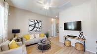 This single-story residence offers a thoughtfully designed open-concept layout with a cohesive, contemporary aesthetic carried throughout. Light wood-look flooring flows seamlessly across the main living areas, complementing the warm neutral palette on the walls and ceilings.

The living room is a bright, welcoming space highlighted by vaulted ceilings, a ceiling fan, and abundant natural light. A bold abstract artwork anchors one wall, while a large wall-mounted television faces a comfortable seating arrangement centered around a round glass coffee table.

The kitchen features crisp white shaker-style cabinetry, light stone countertops, a double-basin sink, and a full suite of stainless steel appliances including a range, over-the-range microwave, and dishwasher. A window above the sink brings in natural light.

The primary bedroom is a serene retreat with an upholstered panel headboard, flanking nightstands with matching lamps, and soft, layered bedding. A second bedroom offers a versatile space with ample natural light and a full dresser with mirror.

The primary bathroom includes a glass-enclosed shower and white vanity cabinetry, while the secondary bathroom features a shower-tub combo and white vanity. Both bathrooms maintain the light, clean finishes found throughout the home.
