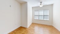 Located at 4301 Cox Pl in Greensboro, NC, this single-floor unit offers a well-organized layout with a neutral color palette and a mix of carpet and hard-surface flooring throughout. The open-concept living and dining area is spacious and bright, featuring plush carpet, a ceiling-mounted light fixture, and a window that allows natural light to fill the space. A ceiling fan with integrated lighting serves one of the carpeted rooms, which also benefits from an outdoor-facing window.

The kitchen is thoughtfully designed with warm honey-toned cabinetry, granite-style countertops, and a peninsula that doubles as a breakfast bar with seating. Black appliances, including a refrigerator, range, and built-in microwave, provide a cohesive look. Light wood-style flooring runs throughout the kitchen, complementing the cabinetry. A pendant lantern fixture above the peninsula adds a decorative touch.

The bathroom features a clean, all-white soaking tub and shower combination with tile surround and light tile flooring. A dedicated laundry room includes washer and dryer hookups, wire shelving for storage, and wood-style flooring. Additional carpeted rooms offer versatile space with crisp white walls and ample room to configure as needed.