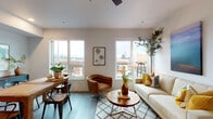 Located at 105 N Killingsworth St in Portland, Oregon, this modern single-floor residence offers a thoughtfully designed layout with clean lines and contemporary finishes throughout. The open-concept living and dining area is bathed in natural light from a generous bank of large windows, offering views of the surrounding Portland neighborhood. Wide-plank hardwood-style flooring runs throughout the space, complemented by crisp white walls and a ceiling fan that add to the bright, airy atmosphere. The streamlined kitchen features two-tone cabinetry in soft sage and white, light countertops, a built-in cooktop, microwave, and ample upper and lower storage, along with open shelving for display. The bedroom is a calm retreat, benefiting from its own window that draws in natural light, while the bathroom includes a clean vanity, toilet, and shower with durable LVP flooring. A dedicated flex area with a street-facing window provides an ideal spot for a home office or reading nook. Additional practical features include a decorative ladder shelving unit and modern hardware and fixtures throughout. The overall aesthetic is contemporary and inviting, making this a well-appointed urban residence in the heart of North Portland.
