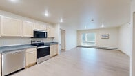 This 3-bedroom, 2-bathroom unit on Center Avenue in Moorhead, Minnesota offers a clean, functional layout across a single floor. Light-toned luxury vinyl plank flooring runs throughout, lending a bright and cohesive feel to every room. The kitchen is well-equipped with light maple cabinetry, dark countertops, and a full suite of stainless steel appliances including a refrigerator, electric range, over-the-range microwave, and dishwasher. An entry closet adjacent to the kitchen provides convenient storage near the main door. The open living area receives natural light through large windows with views of the surrounding neighborhood, and includes a wall-mounted air conditioning unit and baseboard heating for year-round climate control. Each of the three bedrooms is generously proportioned, with the spacious primary bedroom offering a large built-in double closet. The additional bedrooms also feature built-in closets and natural light from windows. Both bathrooms are outfitted with clean, white walk-in shower units with chrome fixtures. The overall design is simple and neutral, creating a move-in ready environment with practical amenities throughout.