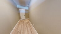 Located at 10 Fieldstone Cmn in Tolland, CT, this three-floor home offers a well-designed layout with two bedrooms and three bathrooms spread across a generous amount of living space. The main floor features an open-concept kitchen and living area, where white shaker cabinetry, stainless steel appliances, a peninsula with a sink, and light hardwood-style flooring create a clean, modern aesthetic with crown molding accents throughout. The living room is highlighted by a fireplace with a classic white mantle, a ceiling fan, and sliding glass doors that invite natural light. The upper floor hosts the spacious primary bedroom, complete with plush carpeting, crown molding, a ceiling fan, and a walk-in closet fitted with wire shelving systems. The bathrooms are finished with light hardwood-style flooring and natural light from windows. The lower level offers a large, open flex space with double doors to the outside, providing versatile use potential. An attached garage with an automatic opener adds everyday convenience. Hallways and staircases connect all three floors seamlessly, with light wood flooring and neutral warm-toned walls giving the home a cohesive, move-in-ready feel throughout.