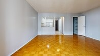 Located at 299 Glenlake Ave in Toronto's sought-after High Park neighbourhood, this efficiently designed single-floor unit makes excellent use of its compact footprint. The living area serves as the heart of the space, showcasing gleaming parquet hardwood flooring in a classic basket-weave pattern that adds warmth and character throughout. A large floor-to-ceiling sliding window wall floods the room with natural light while offering views of the surrounding urban cityscape, creating an open and airy atmosphere. The kitchen is accessed via a pass-through opening from the living area, and features ample white cabinetry — both upper and lower — with light-toned countertops and tile flooring, keeping the space feeling clean and bright. A stainless steel sink is neatly integrated into the counter layout. The bathroom is well-appointed with white mosaic tile flooring, a full soaking tub with a tiled surround in neutral tones, a toilet, and a vanity. A dedicated closet provides convenient built-in shelving, offering practical storage solutions within the unit. With its functional layout, natural light, and classic design details, this unit presents a comfortable and well-organized living space in a vibrant Toronto neighbourhood.