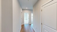 Located at 412 Summer St in Abington, MA, this thoughtfully designed three-bedroom, two-bathroom residence offers a comfortable and modern single-floor layout. The open-concept kitchen and living area serves as the heart of the home, featuring warm hardwood-style flooring, light wood cabinetry extending to the ceiling, white quartz countertops, a center island, and a full suite of stainless steel appliances. A white subway tile backsplash and recessed lighting add a clean, contemporary touch, while large windows flood the space with natural light and outdoor views. The spacious living area continues the hardwood flooring and is lined with multiple windows, creating a bright and airy atmosphere. The three bedrooms are finished with plush carpeting, neutral tones, and large windows that frame pleasant outdoor scenery. Each bedroom includes double-door closets for generous storage. The two bathrooms are well-appointed, with one featuring a soaking tub and shower combo surrounded by crisp white subway tile and polished chrome fixtures, and the other offering a wood-toned vanity, white countertop, and hardwood flooring. A connecting hallway ties the layout together seamlessly, making this a functional and inviting home.