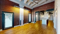 This 1-bedroom, 1-bathroom loft in Memphis, TN showcases a striking industrial-chic aesthetic rooted in its original architectural character. Exposed red brick walls and structural columns define the space throughout, complemented by rich hardwood flooring that flows seamlessly from room to room.

The open-concept living area is immediately impressive, with soaring ceilings featuring white-painted exposed beams and ceiling fans that enhance airflow and add to the loft's character. Multiple windows with plantation-style blinds invite an abundance of natural light, creating a bright and airy atmosphere.

The kitchen is a functional centerpiece, anchored by a generous granite-topped peninsula with an integrated sink — ideal for both meal preparation and casual dining. Dark espresso cabinetry, pendant lighting, and black appliances complete the look, while exposed ductwork overhead reinforces the industrial design theme.

The bedroom offers a spacious, versatile layout with tall ceilings and exposed mechanical elements, maintaining the cohesive industrial style found throughout the unit. Open wall shelving provides practical storage near the kitchen area.

The bathroom is cleanly finished with tile surrounding the tub/shower combo, a granite vanity top, and hardwood-style flooring, offering a polished contrast to the raw elements found elsewhere in the space.