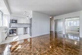 Located in the heart of Toronto's Church-Wellesley Village, this one-bedroom, one-bathroom unit at 100 Gloucester Street offers a well-designed and efficiently laid-out living space. The main living area is generously proportioned, showcasing gleaming parquet hardwood floors in a classic herringbone-style pattern that adds warmth and character throughout. Large windows flood the space with natural light and frame views of the surrounding Toronto skyline, while a baseboard radiator provides comfortable, even heating.

The bedroom is accessed through elegant mirrored sliding doors, which reflect light and enhance the sense of space. It mirrors the same polished parquet flooring and benefits from its own window with city views.

The kitchen is bright and modern, featuring white shaker-style cabinetry extending to the ceiling, a herringbone tile backsplash, light stone tile flooring, and a full suite of stainless steel appliances including a refrigerator, stove, built-in microwave, and dishwasher. Track lighting and a window ensure the kitchen is well-lit throughout the day.

The bathroom is finished in a clean, classic style with white subway tile walls, a stone tile floor, a soaking tub with shower, a vanity with mirror, and a medicine cabinet — offering a bright, functional retreat.
