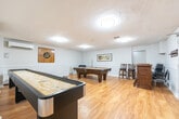 Located at 1363 Lakeshore Rd in Burlington, Ontario, this well-appointed amenity space offers a comfortable and functional layout across a single floor. The space is divided into two primary areas, each designed to serve distinct purposes while sharing a cohesive aesthetic defined by warm hardwood-style flooring, white wainscoting, and neutral walls throughout.

The recreation room provides an inviting atmosphere for leisure and entertainment, featuring a full-size pool table, a shuffleboard table, and a dartboard mounted on a rustic wooden panel. A small bar area with bar stools adds to the social ambiance, while a wall-mounted split air conditioning unit ensures year-round comfort. Flush-mount ceiling lights and a textured ceiling complete the look of this lively gathering space.

Adjacent to the recreation area is a well-lit meeting and dining room, furnished with a large wooden table and padded chairs suitable for group meetings or social dining. Framed artwork decorates the walls, and an additional split AC unit with baseboard heating ensures climate control.

A functional kitchen supports the space with warm wood cabinetry, granite-style countertops, a stove, refrigerator, microwave, sink, and a central island — ideal for catering or light meal preparation during events.
