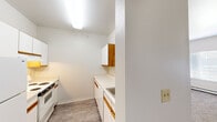 Located at 999 E First Ave in Broomfield, Colorado, this one-bedroom, one-bathroom residence offers a practical and efficiently designed single-floor layout. The galley-style kitchen is outfitted with white cabinetry accented by warm wood trim, white appliances including a refrigerator and electric range, a single-basin sink, and light wood-look flooring that keeps the space feeling clean and bright. Upper and lower cabinet storage provides ample organization for everyday needs. The living room offers a comfortable, open area with plush carpeting and neutral white walls, creating a versatile canvas for personalization. A hallway connects the main living areas to the private spaces of the unit. The bedroom is a well-proportioned retreat featuring soft carpeting, a baseboard heater, and a window that invites natural light and outdoor views. A walk-in closet with built-in shelving and hanging rods provides generous storage. The bathroom includes a full tub and shower combination with a handheld showerhead, a single vanity with white cabinetry and a large mirror, and overhead lighting. Throughout the residence, the consistent use of neutral tones and clean finishes creates a cohesive, move-in ready environment.