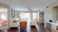 This single-story residence offers a cohesive and functional layout designed for comfortable everyday living. The kitchen is equipped with dark espresso cabinetry, light stone-look countertops, and black appliances, including a refrigerator, electric range, dishwasher, and built-in microwave. A peninsula with bar seating connects the kitchen to the dining area, creating an open, social atmosphere ideal for entertaining. The adjoining dining space features hardwood-style flooring and is anchored by a statement pendant light overhead.

The bedrooms are carpeted for comfort and each includes a ceiling fan with light fixture. The primary bedroom features a walk-in closet and direct access to an en-suite bathroom equipped with a vanity, dual medicine cabinets, a large mirror, and a walk-in shower. A second full bathroom includes a tub-shower combination, a dark-cabinetry vanity with a light countertop, and wood-style flooring. Additional bedrooms offer natural light through large windows, ample closet space, and a neutral color palette throughout. A laundry area with washer and dryer hookups is also present. The textured ceilings and warm tones lend the space a consistent, inviting character.