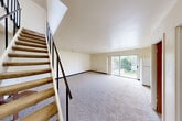 Located at 121 E Hoover in Ann Arbor, MI, this two-story, 2-bedroom, 3-bathroom home offers a practical and functional layout spread across two floors. The main level features a combined living and dining area with neutral-toned carpet, crisp white walls, and a sliding glass door that fills the space with natural light and provides direct access to a private balcony with outdoor views. The kitchen is positioned adjacent to the living area and is equipped with white appliances, cabinetry, and tile flooring that transitions smoothly from the carpeted living space. A staircase with a metal railing connects the two floors. Upstairs, the two bedrooms are generously sized, each with soft carpeting, large windows with vertical blinds allowing ample natural light, and dedicated closet space. The primary bedroom is notably spacious and features its own closet area with built-in shelving and hanging rods. Throughout the home, six closets in total offer abundant storage. The three bathrooms include tiled flooring with clean, functional fixtures. A textured ceiling is featured in select rooms upstairs. The home's neutral color palette and straightforward layout create a clean, move-in-ready atmosphere well-suited for Ann Arbor living.