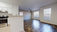 This single-story space features a thoughtfully designed open-concept layout that seamlessly connects the kitchen and living area. Dark wood-style flooring runs throughout the main living spaces, creating a warm, cohesive aesthetic, while light ceramic tile anchors the kitchen and bathroom areas.

The kitchen is well-appointed with crisp white cabinetry, granite-style countertops, a classic subway tile backsplash, and stainless steel appliances including a range with overhead ventilation. A peninsula counter with a built-in sink extends into the living area, providing a natural division between the two spaces while maintaining an open feel.

The living area is bright and airy, benefiting from natural light through blinded windows and a ceiling fan overhead. A dedicated bedroom features its own window with outdoor views, a ceiling fan, and access to a walk-in closet equipped with wire shelving for organized storage.

The bathroom offers a full tub and shower combination with tiled surrounds, a granite-topped vanity, a small window for natural light, and tile flooring. Throughout the space, neutral tones and clean lines create a consistent, functional atmosphere suited to a variety of furnishing styles.