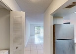 Located at 300 NW 111th Pl in Sweetwater, Florida, this single-floor unit presents a straightforward, functional layout designed to maximize usability across its living spaces. The interior is finished with large-format white ceramic tile flooring throughout, creating a cohesive, clean aesthetic that reflects light and contributes to a bright, airy feel.

The living area is open and generously proportioned, featuring a ceiling fan with integrated lighting and a sliding glass door that opens to an outdoor view, drawing in natural light and providing a seamless connection to the exterior. A pass-through opening connects the living space to the kitchen, which is equipped with stainless steel appliances—including an electric range with a ventilation hood and a full-size refrigerator—white cabinetry with brushed nickel hardware, white countertops, and a subway tile backsplash.

The bedrooms are well-lit, each with tiled flooring and windows that allow natural light to filter in, offering simple, versatile spaces. The bathrooms feature tub-shower combinations with warm-toned tile surrounds and chrome fixtures, providing practical, clean finishes. A textured ceiling runs throughout the unit, and the overall palette of whites and neutrals gives the space a consistently light and open character.