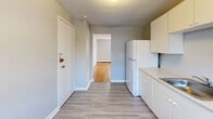 Located on Vinal Street in Boston's Brighton neighborhood, this well-maintained one-bedroom, one-bathroom unit offers a practical and comfortable layout across a single floor. The living room is bright and inviting, featuring warm hardwood flooring and a large window that allows natural light to fill the space, creating an open and airy ambiance. The combined dining and kitchen area transitions seamlessly from the living space, showcasing light gray vinyl plank flooring, white cabinetry with ample upper and lower storage, a stainless steel sink, white appliances including a refrigerator and electric range, and a window overlooking the surroundings. The bedroom is a comfortable size, carrying the same gleaming hardwood floors found throughout the living areas, complemented by a window with neighborhood views and baseboard heating. A hallway connects the bedroom to the full bathroom, which is a standout feature of the unit — dressed in classic mint-green subway tile with black accent trim, a soaking tub, pedestal sink, and a mosaic tile floor, all contributing to a charming retro aesthetic. Three closets throughout the unit provide generous storage. The neutral gray walls and clean finishes give the space a move-in-ready feel.