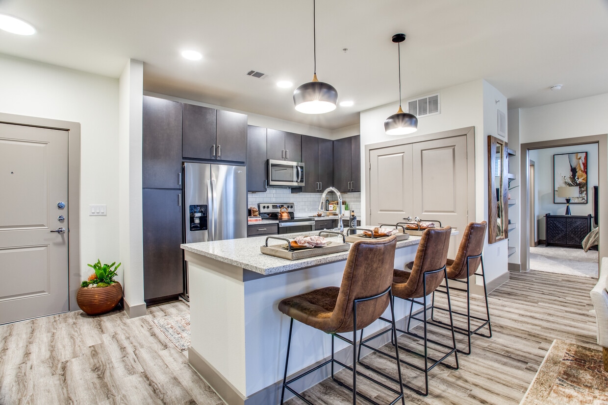 Kitchen with espresso cabinetry, speckled granite countertops, white subway tile backsplash, stainless steel appliances, and hard surface flooring - Avalon Benbrook