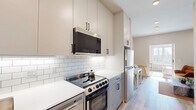 Located at 1457 N Main St in Los Angeles, CA, this thoughtfully designed one-bedroom, one-bathroom unit makes excellent use of its compact footprint. Light wood-look flooring runs throughout, lending a cohesive and contemporary feel to every room.

The kitchen is a standout feature, outfitted with two-tone cabinetry in a warm neutral finish, white subway tile backsplash, and a full suite of stainless steel appliances including a range, over-the-range microwave, dishwasher, and refrigerator. Clean white quartz-style countertops and matte black hardware complete the modern aesthetic.

The living room offers a comfortable, open layout with access to a sliding barn-style door with frosted glass panels, adding an elegant and space-conscious divider between areas.

The bedroom is a bright, welcoming retreat featuring a large window that frames views of the Los Angeles cityscape, allowing ample natural light to fill the room. A sliding frosted-glass barn door provides stylish separation, and two closets offer practical storage solutions.

The bathroom is clean and minimal, featuring light wood-look flooring, a tub/shower combination, a sleek wall-mounted vanity with an illuminated mirror, and matte black accent hardware throughout. The arched ceiling detail adds a subtle architectural touch to this well-appointed space.