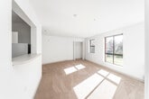 This single-floor residential unit offers a clean, functional layout designed to maximize comfort and practicality. The living area is generously proportioned, featuring warm neutral-toned carpeting and crisp white walls that create a bright, welcoming atmosphere. Multiple windows throughout the space flood the interior with natural light and offer pleasant views of surrounding greenery, including mature trees and open lawn areas — particularly appealing during the fall season when foliage is visible.

The galley-style kitchen is efficiently organized, featuring light wood cabinetry, ample counter space, and full-size white appliances including a refrigerator, dishwasher, and electric range. Tile flooring in the kitchen provides a practical contrast to the carpeted living and sleeping areas.

The bedrooms are well-sized, each with soft carpeting, neutral walls, and access to closet storage. One bedroom includes a walk-in style closet, offering additional organizational capacity. The rooms receive good natural light through windows overlooking the exterior landscape.

The bathroom is neatly appointed with tile flooring, a tub and shower combination with tiled surround, a vanity with sink, and standard fixtures. The overall layout of the unit is straightforward and practical, connecting all living spaces through a central corridor. The unit presents a move-in ready environment suitable for everyday residential living.