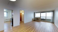 This 2-bedroom, 1.5-bathroom residence offers a well-organized single-floor layout designed for comfortable urban living. The open living area is immediately welcoming, featuring light-toned hardwood-style flooring that runs throughout the space, creating a clean and cohesive aesthetic. Large floor-to-ceiling windows flood the living room with natural light and provide sweeping city views, giving the unit an airy, elevated feel. A wall-mounted climate control unit ensures year-round comfort. The living area flows naturally toward a hallway that connects the bedrooms and bathrooms, maintaining a logical and efficient floor plan. The kitchen is accessible from the main living space and features cabinetry that provides ample storage. The 1.5-bathroom configuration includes a full bath and a convenient half bath, adding practicality for residents and guests alike. Crisp white walls throughout the unit enhance the brightness brought in by the generous window line. The overall ambiance is clean, modern, and move-in ready, making this a highly functional residence that balances open communal areas with private sleeping quarters in a compact yet thoughtfully designed footprint.
