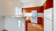 Located at 825 N Sixth Ave in Phoenix, AZ, this one-bedroom, one-bathroom residence offers a well-organized single-floor layout designed for comfortable everyday living. The kitchen is a standout feature, showcasing warm medium-toned wood cabinetry that extends to the upper walls, white appliances including an electric range and over-the-range microwave, clean light countertops, and a double-basin sink positioned beneath a window with vertical blinds that invite natural light. A peninsula counter provides additional workspace and creates a natural division between the kitchen and the main living area. Light wood laminate flooring runs throughout the main living and kitchen spaces, lending a clean, cohesive feel. The bedroom offers a carpeted floor for added comfort, a large window with vertical blinds for natural light, and a double sliding closet providing ample storage. The bathroom features wood-toned cabinetry with a vanity, a large mirror, and wood-look flooring, maintaining a consistent warm aesthetic throughout. Neutral wall tones and tall ceilings across the space contribute to an open and airy ambiance. A connecting hallway links the main areas efficiently, rounding out this functional and inviting Phoenix residence.