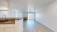 Located at 6530 Independence Ave in the Canoga Park neighborhood of Los Angeles, this one-bedroom, one-bathroom unit is laid out on a single floor with a clean, modern aesthetic throughout. Light wood-style flooring runs continuously across all rooms, contributing to a bright and cohesive feel.

The open-concept kitchen and living area forms the heart of the unit. The kitchen is equipped with stainless steel appliances including a refrigerator, microwave, and range, complemented by white cabinetry, a gray stone-toned countertop, and a peninsula with a built-in sink that provides both workspace and a casual dining option. Recessed lighting and open upper shelving add functional style. The adjacent living area is spacious and airy, featuring crown molding, a ceiling fan, and a sliding glass door with vertical blinds that opens to a balcony, inviting natural light and outdoor views.

The bedroom is a comfortable, well-proportioned retreat finished with the same light flooring, crown molding, a ceiling fan, and a window fitted with blinds that allows natural light while maintaining privacy.

The bathroom is clean and efficiently designed, featuring a combined shower and tub, a vanity with storage, and consistent light wood flooring that ties the space together. The unit's overall palette of white walls and light finishes creates a fresh, move-in-ready environment.