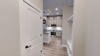 This thoughtfully designed single-floor residence offers 1 bedroom and 2 bathrooms across a compact yet efficient layout. Light-toned luxury vinyl plank flooring flows seamlessly throughout the living areas and bedroom, lending a clean, cohesive aesthetic to the entire space.

The kitchen and living area form the heart of the home, showcasing an impressively appointed kitchen with floor-to-ceiling shaker-style cabinetry in a warm greige finish, dark granite countertops, a white subway tile backsplash, and a full suite of stainless steel appliances including a French door refrigerator, range, and built-in microwave. A central island with a dark countertop provides additional prep space and casual seating. Pendant lighting with matte black accents adds a modern industrial touch overhead.

The entrance features a built-in mudroom-style nook with shelving and hooks, offering practical storage from the moment you step inside. The bedroom is generously sized, fitted with a ceiling fan and large windows that invite ample natural light.

Both bathrooms are finished with marble-inspired tile. One features a walk-in shower with large-format stone tile walls, mosaic tile flooring, and a built-in bench, while the other includes a white vanity with dark countertop, black hardware, and a framed mirror. An in-unit stacked washer and dryer round out this well-equipped residence.