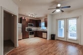 Located at 131 Ponce de Leon Ave NE in Atlanta, GA, this single-floor residential unit sits in the heart of the dynamic Old Fourth Ward neighborhood, offering convenient access to the city's dining, entertainment, and cultural amenities. The layout is efficient and well-organized, connecting living areas through a clean, light-filled hallway finished with warm hardwood-style flooring and neutral white walls.

The kitchen is a standout feature, outfitted with rich dark wood cabinetry, granite-style countertops, and a full suite of stainless steel appliances including a refrigerator, electric range, microwave, and dishwasher. Track lighting overhead and a window with natural light make this a bright and functional cooking space.

The living area continues the hardwood-style flooring and is anchored by a ceiling fan with integrated lighting, providing comfort and airflow. A carpeted bedroom offers a softer, quieter retreat, with an open doorway connecting back to the main living and kitchen area.

The bathroom is finished with neutral tile flooring and a tiled tub-and-shower surround in a warm beige tone, complemented by a dark-finish vanity with stone-style countertops and chrome fixtures. The overall palette throughout the unit is clean and contemporary, with white walls and consistent finishes creating a cohesive, move-in-ready atmosphere.