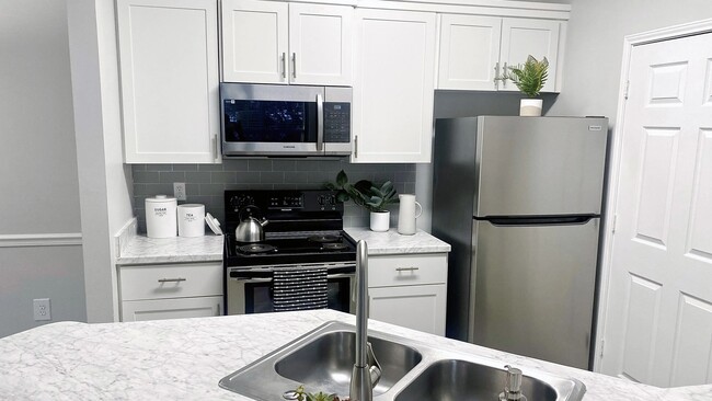 White cabinetry and stainless-steel appliances in our open-concept kitchens are complimented by Carrara marble inspired countertops in select homes. - 100 South Luxury Apartments