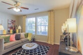 Located at 504 Cap Stone Arch in Chesapeake, Virginia, this single-floor residence offers a well-appointed layout designed for comfortable everyday living. The kitchen is a standout space, featuring rich dark cabinetry, granite countertops, stainless steel appliances, and a central island with bar seating — all set atop warm hardwood flooring that flows seamlessly into the living area. The living room is bright and welcoming, with large windows that invite abundant natural light and views of the surrounding greenery, complemented by a ceiling fan overhead. Multiple bedrooms provide generous accommodations, each carpeted and fitted with large windows that enhance the sense of space and airflow. One bedroom features a striking accent wall with a slatted dark wood headboard panel and ample natural light, while a second bedroom offers sliding glass door access to an outdoor area. Two full bathrooms are finished with tile flooring, dark vanity cabinetry, soaking tubs with tile surrounds, and shower-tub combinations. A dedicated in-unit laundry room houses a full-size washer and dryer with built-in shelving for additional storage. Throughout the residence, a cohesive design palette of neutral tones, dark fixtures, and thoughtful finishes creates a polished and functional living environment.