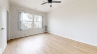 Located at 245 N Kenmore Ave in the Los Feliz neighborhood of Los Angeles, this efficiently designed single-floor unit offers a well-planned layout comprising a living room, kitchen, bathroom, and hallway. Light wood vinyl flooring runs throughout, creating a warm and cohesive aesthetic across the space.

The living room is bright and airy, highlighted by a sleek ceiling fan, crisp white walls, and a striking whitewashed brick accent wall that adds character and texture. Large windows invite an abundance of natural light and frame views of palm trees and the surrounding Los Angeles streetscape, enhancing the open feel of the room. A mirrored closet further reflects light and adds to the sense of space.

The kitchen features gray shaker-style cabinetry with modern hardware, clean white countertops, and light wood flooring that continues from the main living area. A full-size stainless steel refrigerator and a window with vertical blinds complete the functional and contemporary kitchen design.

The bathroom is finished in a clean, modern style with gray shaker vanity cabinetry, a white countertop with an undermount sink, chrome fixtures, a framed mirror, and a full bathtub with shower. Light wood-tone flooring ties the bathroom seamlessly to the rest of the unit.

Overall, the space presents a bright, modern aesthetic with thoughtful finishes throughout.