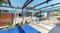 This outdoor amenity area offers a well-appointed, resort-inspired environment designed for relaxation and recreation under open California skies. The space is anchored by a sparkling swimming pool lined with lounge chairs, providing ample room for sunbathing along a clean concrete deck. Adjacent to the pool, a bubbling spa with stainless steel handrails offers a more intimate retreat, framed by warm wood privacy screens that add a refined architectural contrast to the contemporary grey-toned surroundings.

A shaded dining and lounge zone features multiple seating arrangements beneath vibrant teal patio umbrellas, creating comfortable outdoor gathering spots ideal for socializing. A dedicated recreation area, covered by a sleek modern pergola, houses a ping-pong table and is bordered by planter boxes with tropical foliage, reinforcing the resort-like atmosphere. Towering palm trees punctuate the skyline throughout, enhancing the Southern California ambiance.

The overall design blends modern architecture with natural materials, including rich wood slatted screens and lush greenery, creating a cohesive, inviting outdoor environment bathed in abundant natural sunlight.