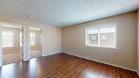 Located at 2701 Main St in Forest Grove, Oregon, this single-floor unit offers a well-organized layout designed for comfortable, everyday living. The living area is a standout feature, showcasing rich, dark hardwood-style flooring that extends throughout the main living spaces, warm neutral wall tones, and a textured ceiling. Multiple windows allow natural light to fill the room, creating a bright and open atmosphere with views of the surrounding neighborhood.

The kitchen is thoughtfully appointed with natural wood cabinetry featuring distinctive grain detailing, granite-style countertops, and stainless steel appliances including a range and refrigerator. The hardwood-style flooring continues seamlessly into this space, maintaining a cohesive look throughout.

The bedrooms are carpeted in a neutral tone and each includes a closet with panel doors, providing practical storage. A wall-mounted heating unit is present in at least one bedroom, ensuring year-round comfort.

The bathroom is clean and functional, featuring tile flooring in an earthy tone, a full tub-shower combination with a white surround, and a vanity with ample storage. The overall aesthetic of this unit is consistent and understated, with a neutral color palette that offers a versatile canvas throughout every room.