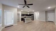 Located along the Lyndon B. Johnson Freeway Frontage Road in Grand Prairie, Texas, this single-floor unit offers a well-designed, modern interior with a cohesive neutral color palette throughout. The open-concept living and kitchen area forms the heart of the space, anchored by light wood-style flooring and a ceiling fan with recessed lighting overhead. The kitchen is a standout feature, equipped with dark espresso-toned shaker cabinets, granite-style countertops, a central island with a sink, stainless steel appliances including a gas range, built-in microwave, and refrigerator, as well as pendant lighting and an adjacent open pantry with built-in shelving. The living area flows seamlessly from the kitchen, providing an open and airy feel with ample room for comfortable furnishings. A secondary room features the same light wood-style flooring and a window that brings in natural light, making it well-suited for use as a bedroom or flex space. The primary bedroom is carpeted and generously sized, with a ceiling fan, walk-in closet, and direct access to the hallway. The bathroom is finished with dark cabinetry, granite-style counters, and a full tub-shower combination with tiled surround. Throughout, clean lines and modern finishes create a cohesive and functional living environment.