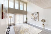 Located at 4001 Lakemont Dr in College Park, GA, this two-story, 2-bedroom, 2-bathroom home offers a well-designed layout spread across two floors. The main level immediately impresses with a dramatic living area boasting soaring double-height ceilings and a generous wall of windows and sliding glass doors, flooding the space with natural light. Hardwood-style flooring runs throughout the main level, complementing the neutral, warm color palette.

The kitchen is efficiently laid out with white cabinetry, granite-style countertops, black appliances, and a window that brings in additional natural light. Two full bathrooms feature wood-look flooring, white vanities with ample storage, and tub-shower combinations.

Upstairs, an open hallway landing with ornate iron railings overlooks the main level and provides access to both bedrooms. Both bedrooms feature plush carpet, textured ceilings, windows with natural light, and closet space. The generously sized primary bedroom offers comfortable proportions and a relaxed, neutral ambiance.

With four hallways providing smooth circulation between spaces, a central staircase, and a cohesive design language throughout, this home balances practical functionality with an inviting, light-filled atmosphere.