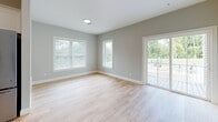 Located in Upton, MA, this single-floor residence offers a thoughtfully designed layout with clean finishes throughout. The kitchen is a standout feature, boasting white shaker-style cabinetry, a classic subway tile backsplash, granite countertops with an island peninsula, stainless steel appliances, and light hardwood flooring that flows seamlessly into the adjacent living area. The spacious living area is filled with natural light from multiple windows and a sliding glass door that opens to a private outdoor deck, providing pleasant views of the surrounding greenery. The bedrooms are finished with plush neutral carpeting and soft gray walls, offering a calm and comfortable atmosphere. Each bedroom includes dedicated closet space with built-in shelving and rods for organized storage. The bathrooms are well-appointed with white vanity cabinetry, granite countertops, large mirrors, and durable tile flooring. Chrome fixtures and towel bars add polished detail throughout. The consistent use of soft gray tones, white trim, and quality materials across all rooms creates a cohesive, modern aesthetic that is both functional and inviting.