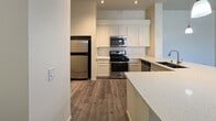 This well-appointed 2-bedroom, 2-bathroom residential unit spans 1,120 square feet on a single floor, offering a thoughtfully designed layout with modern finishes throughout. The open-concept kitchen and living area serves as the heart of the home, featuring wood-look plank flooring, white shaker-style cabinetry, quartz countertops, a kitchen island, and stainless steel appliances including a gas range, microwave, and refrigerator. The living room is bright and spacious, with access to an outdoor balcony through sliding glass doors that frame scenic outdoor views. Both bedrooms are carpeted and include ceiling fans, natural light from windows with blinds, and dedicated closet space. The primary bedroom measures 170 square feet and is accompanied by an en suite bathroom showcasing a dual-sink vanity with white cabinetry, quartz countertops, a framed mirror, and a walk-in glass-door shower, as well as a walk-in closet. The second bathroom offers a full tub-shower combo with white tile surround. A dedicated in-unit laundry room with wood-look flooring and shelving adds everyday convenience. The unit includes three total closets, providing ample storage throughout.