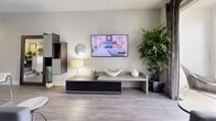 This 2-bedroom, 1-bathroom model townhome at St. Tropez Luxury Townhomes and Villas in Plantation spans 1,340 square feet across three floors. The ground floor (290 sq ft) features a dedicated laundry area with full-size washer hookups and staircase access. The main living level (710 sq ft) showcases an open-concept kitchen and living room with light wood-style flooring, vaulted ceilings with recessed track lighting, and a tray ceiling detail. The gourmet kitchen features white shaker cabinetry, stainless steel appliances, a mosaic tile backsplash, and a granite waterfall island with bar seating. The living area is bright and airy, with sliding glass door access and a ceiling fan. The upper floor (340 sq ft) hosts both bedrooms and the full bathroom. The primary bedroom (170 sq ft) features vaulted ceilings, plush carpeting, a ceiling fan, and a walk-in closet. The secondary bedroom offers similar comfort with carpeted floors. The shared bathroom includes a granite vanity, white cabinetry, wood-style flooring, and a tub-shower combination with white tile surround.
