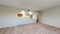 Located in Largo, Florida, this single-floor unit offers a practical and well-organized layout designed for comfortable living. The spacious living room is finished with plush carpeting and features large windows with vertical blinds that allow natural light to fill the space, along with a sliding glass door that opens to an outdoor area. A textured ceiling completes the room's clean, neutral aesthetic.

The kitchen is accessible via a pass-through counter that opens directly to the living area, creating an open and connected feel. It is equipped with warm-toned wood cabinetry, white appliances including an electric range and dishwasher, a double sink, and durable wood-look vinyl flooring that extends into the adjacent spaces.

The bedrooms are generously sized with soft carpeting and neutral wall tones, offering a calm and restful environment. A hallway connects the main living spaces to the private areas of the unit.

The bathrooms are clean and functional. One features a full tub-and-shower combo with white square tile surround and chrome fixtures, while the second includes a wood-cabinet vanity, toilet, and wood-look flooring with a natural light source from a window. A louvered closet door adds a classic touch to the layout.