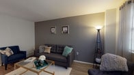 This two-floor residence offers a thoughtfully arranged layout that balances comfort and functionality throughout. The living room serves as the heart of the home, featuring warm hardwood-style flooring, a bold charcoal accent wall adorned with framed artwork, and ample space for relaxed seating and entertaining. Natural light filters in through a window, complementing the warm ambient lighting.

Adjacent to the living area, the dining space accommodates a round glass-top table beneath a ceiling fan with integrated lighting, creating an inviting setting for meals. The kitchen is well-equipped with white shaker-style cabinetry, a full suite of stainless steel appliances — including a range, microwave, dishwasher, and refrigerator — and a clean, light-toned countertop, all set on durable hardwood-style flooring.

The primary bedroom is a serene retreat with soft carpeting, light neutral walls, and multiple windows that allow natural light to fill the room. A second bedroom offers similarly comfortable carpeted flooring and features a large built-in closet with bifold doors. The full bathroom includes a tub-shower combination, a white vanity with storage, and wood-look flooring, providing a clean and practical space.